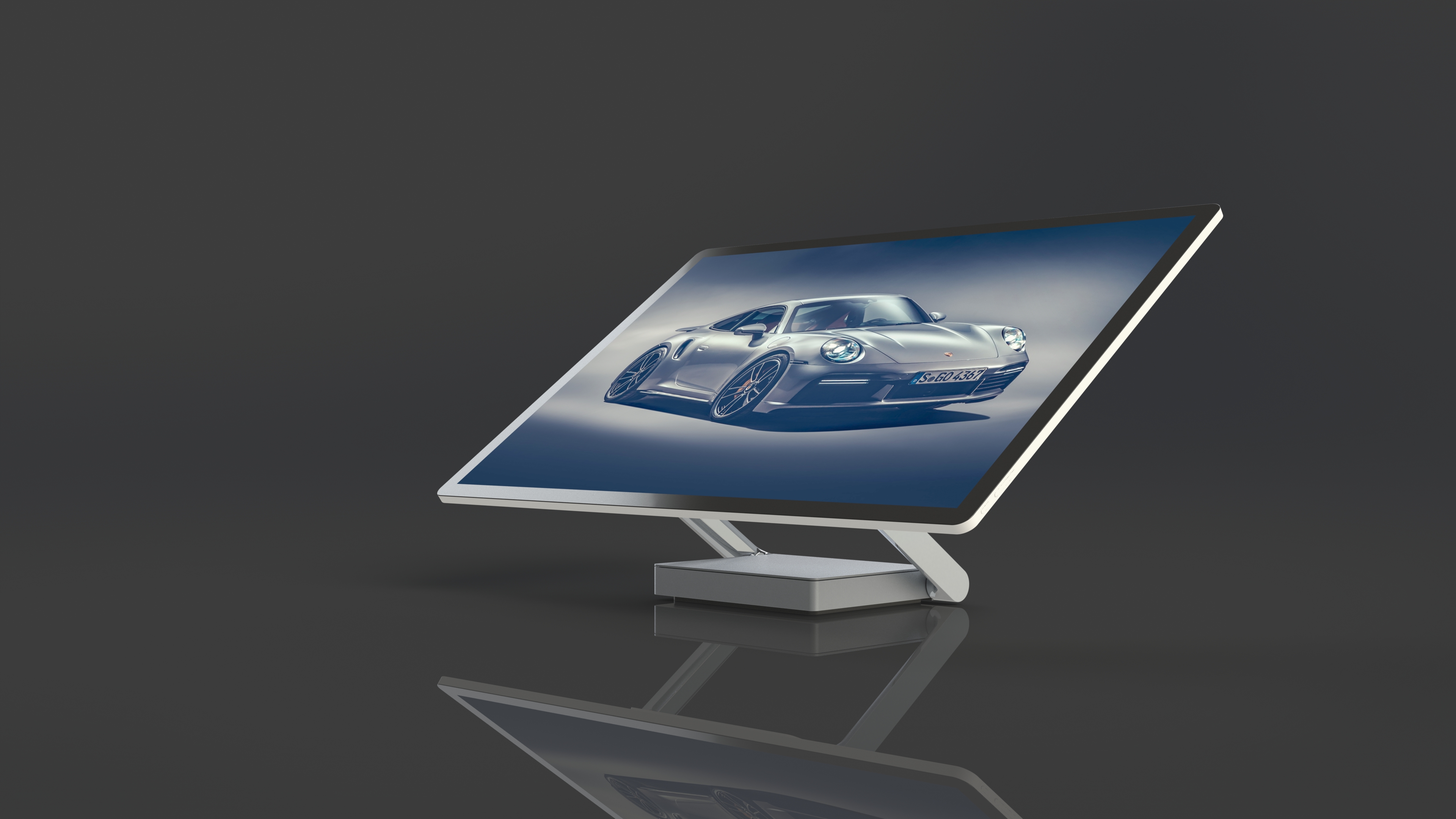 Render of an all-in-one desktop with a Porsche 911 on the angled screen